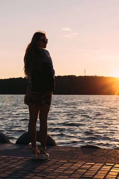 A menina na costa do lago admira o pôr do sol e o shi — Fotografia de Stock