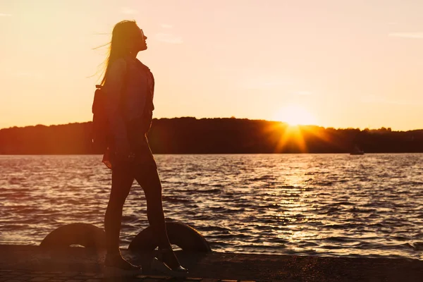 Göl kıyısında yürüyen bir kız. Gün batımı. siluet — Stok fotoğraf