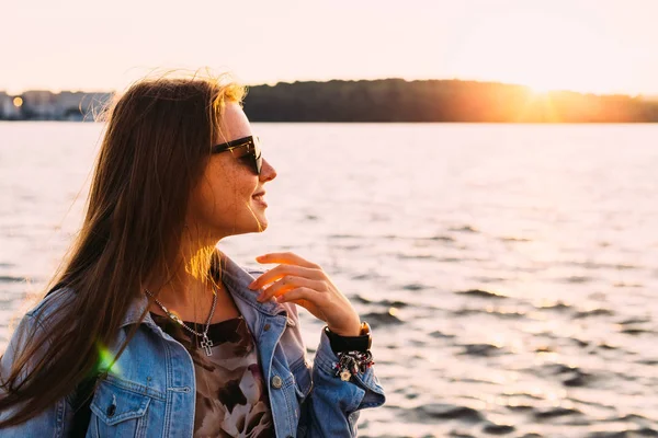 Дівчина з веснянками і сонцезахисними окулярами на березі озера. навіть — стокове фото