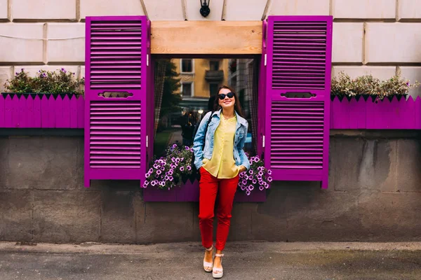 Стильная девушка в солнцезащитных очках у фиолетового окна с жалюзи. — стоковое фото
