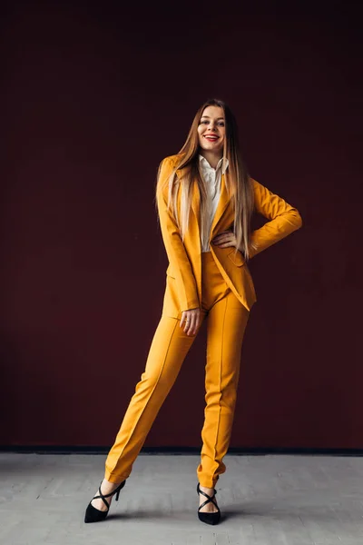 Girl in yellow suit and make-up posing on a red background. Fas — Stock Photo, Image