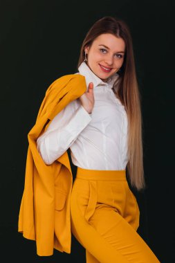 kız elinde bir ceket tutar ve kameraya bakar. Sarı 