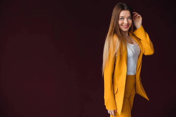 young woman in a yellow suit with long hair cute smiles at the w