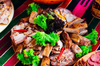 Ahşap bir plaka üzerinde dilimlenmiş jambon ve pastırma ve lettuc ile dekore