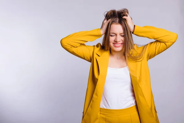 Sterke hoofdpijn in een jonge vrouw in een geel pak. witte blauw — Stockfoto