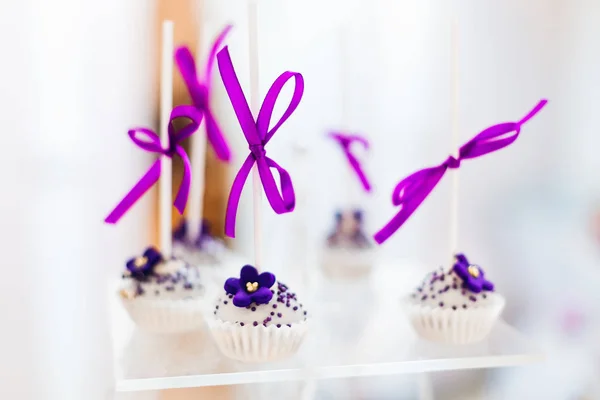 Menekşe çiçekler ve teyp ile süslenmiş cupcakes, bir yasağı üzerinde hizmet — Stok fotoğraf