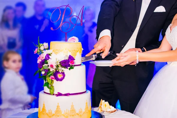 Newlyweds cut delicious wedding cake with frosting and flowers.