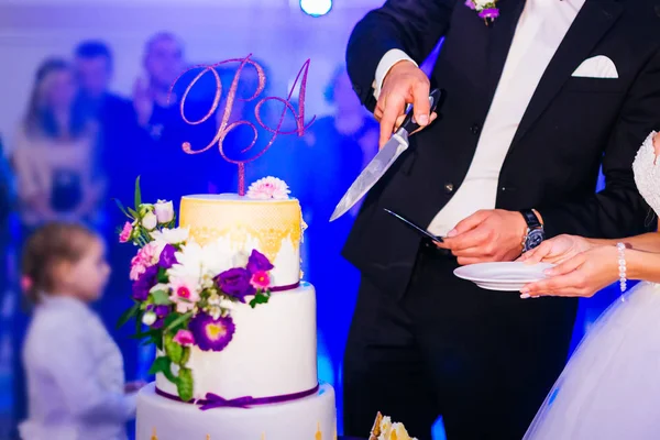 Nowożeńcy wyciąć pyszne ciasto weselne z lukier i kwiaty. — Zdjęcie stockowe