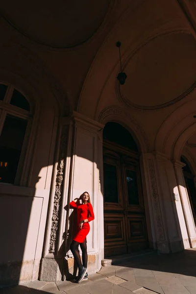 Девушка в красном платье рядом с большой деревянной дверью в коридоре остроумие — стоковое фото