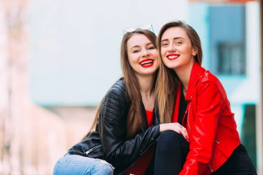 Deri ceketli, parlak makyajlı güzel kızlar oturuyor.