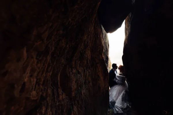 Novomanželé ve svátečním oblečení se chtějí líbat v kamenném tunelu. jsme — Stock fotografie