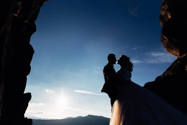 Silhouette de nouveaux mariés s'embrassant sur un fond de cl — Photo