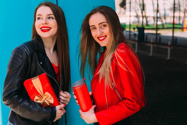 Ragazze in giacca di cuoio in possesso di una scatola rossa e una termocoppa rossa. — Foto Stock