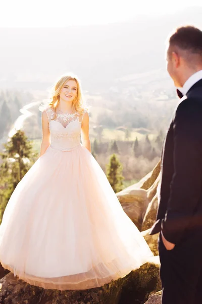 Braut in einem Kleid mit Spitze sieht den Bräutigam auf einem Hintergrund von — Stockfoto