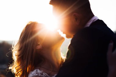 Yeni evlilerin profili ve aralarındaki güneş ışınları. Ki