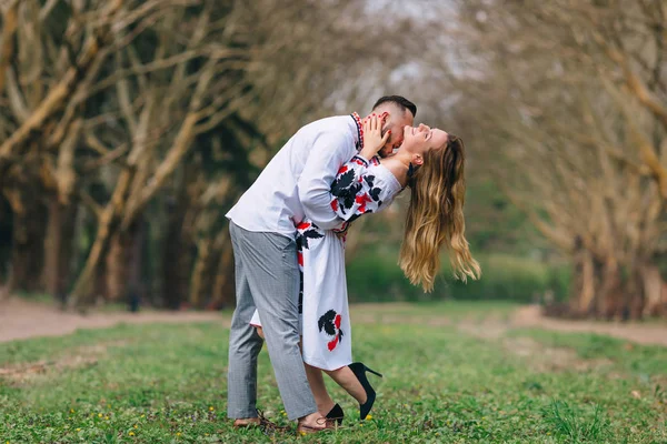 Der Kerl umarmt und küsst das Mädchen. bestickte Kleidung. Park. — Stockfoto