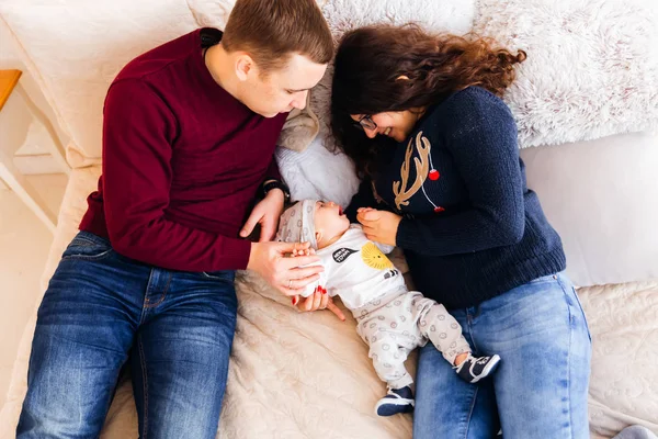 Ein Blick von oben auf die Eltern und das Baby, die auf dem Bett liegen und — Stockfoto