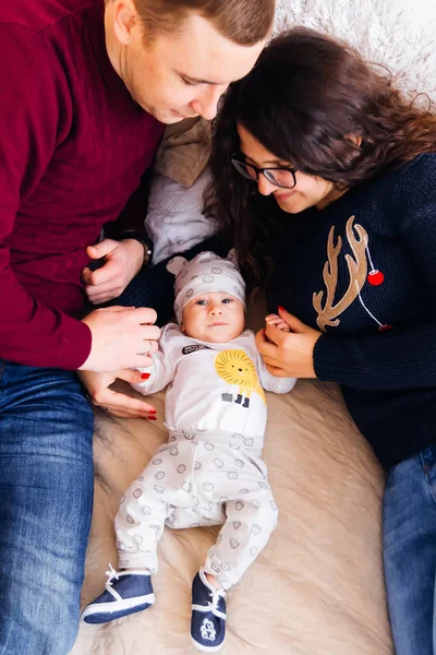 A top view of young parents and a baby who lie on the bed and sp — Stock Photo, Image