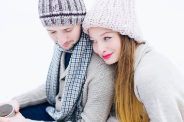 sıcak giysiler içinde kız ve adam karda oturup, adam tutar 