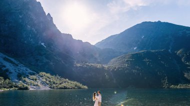 Güzel dağlar, göl ve güneş ışığı. Erkek ve kız yüz yüze.