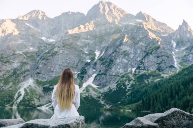 kayalık dağlar ve göl görünümü. beyaz bir kızın arka görünümü