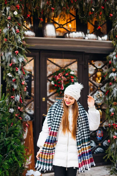 Ένα όμορφο κορίτσι με ένα λευκό χειμωνιάτικο μπουφάν, ένα ζεστό κασκόλ και καπέλα στο — Φωτογραφία Αρχείου