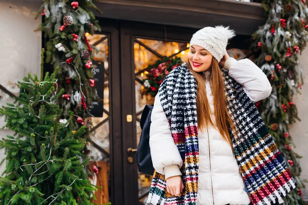 A girl in winter clothes and a backpack looks down and corrects — Stock Photo, Image