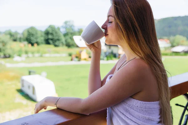 Дівчина заплющила очі і п'є гарячу каву на балконі — стокове фото
