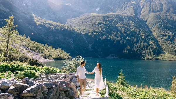 Dívka a chlap drží za ruce a chodí po kamenné stezce s výhledem — Stock fotografie