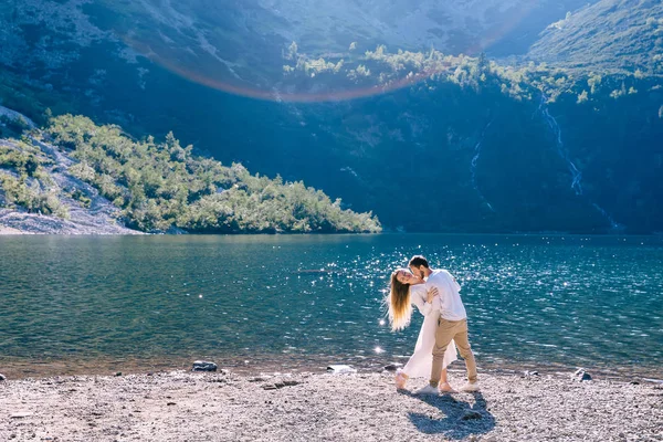 Der Kerl umarmt das Mädchen und sie beugt sich am Ufer des Sees zurück. mo — Stockfoto
