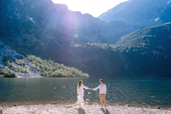 Chlap a dívka drží za ruce a dívá se na sebe n břehu — Stock fotografie