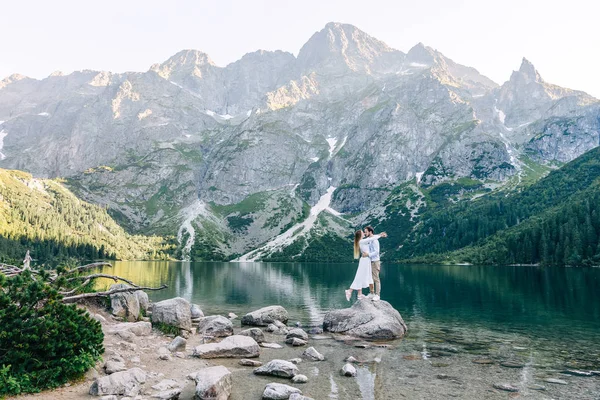 Verliebtes Paar umarmt sich und steht auf Steinen auf dem Hintergrund des Sees — Stockfoto