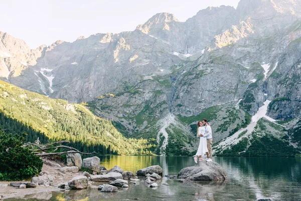 Verliebtes Paar umarmt sich auf Steinen in der Nähe des Sees auf Bergen — Stockfoto