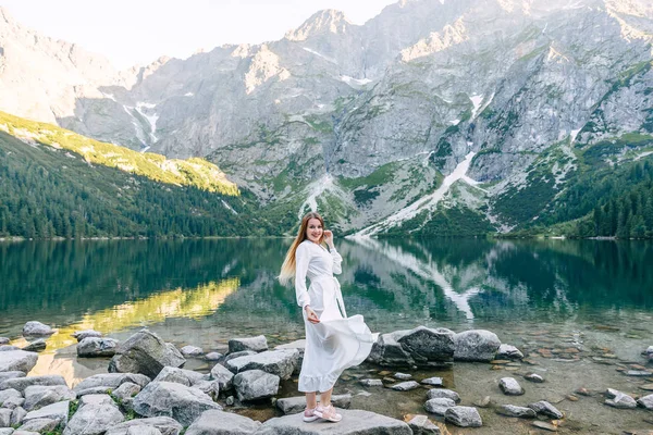 Mädchen in weißem Kleid steht am Ufer eines Sees. Reisen t — Stockfoto