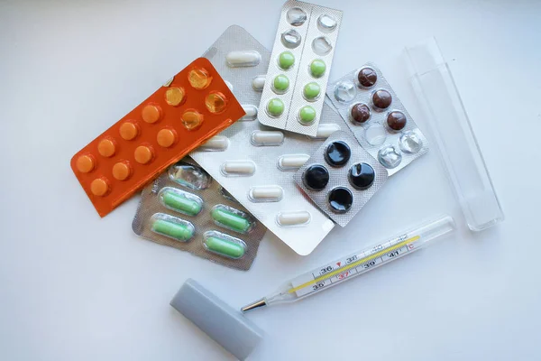 En närbild av piller i olika förpackningar på en vit yta och — Stockfoto