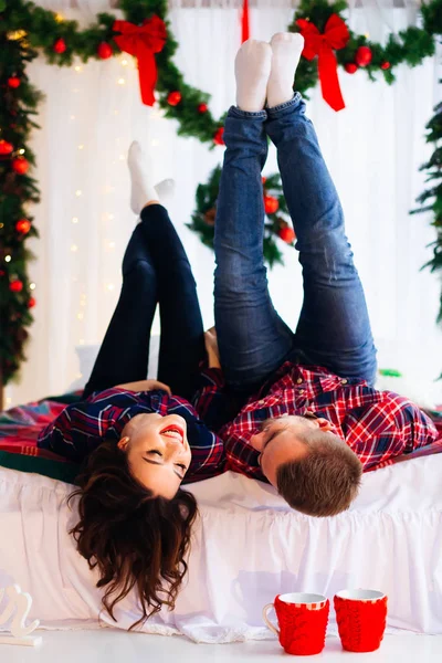Pareja en el amor divertirse mientras está acostado en la cama con la Navidad decora — Foto de Stock