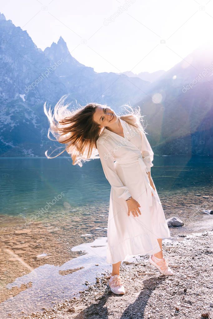 girl in a white dress near the lake waving her hair on a backgro