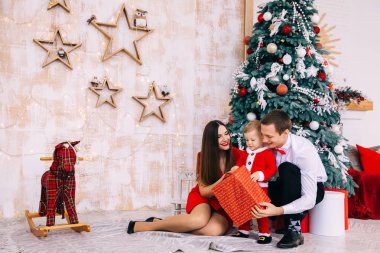 Noel ağacının yanında hediyeleri açan mutlu bir aile. bebek sade