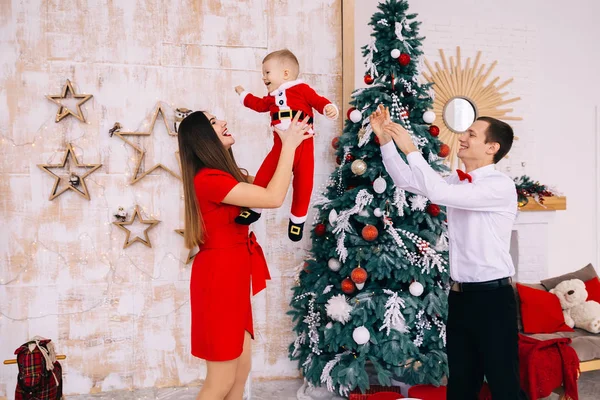 Ouders spelen met de baby bij de kerstboom. Moeder ca. — Stockfoto