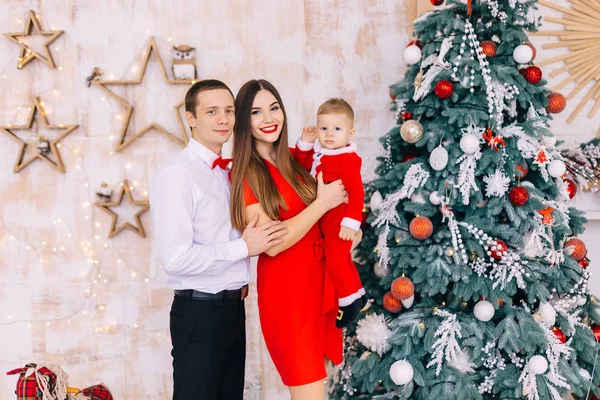 Ouders en baby in feestelijke kleding op zoek naar camera in de buurt van schoonheid — Stockfoto