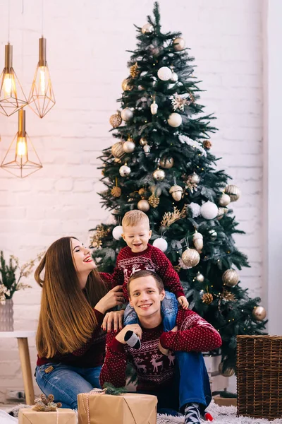 Pais e pequeno filho sentado perto da bela árvore de Natal e — Fotografia de Stock