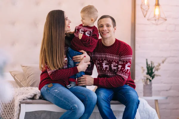 Família feliz sentado na cama e olhando para a câmera. Natal tre — Fotografia de Stock
