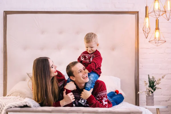 Papa en mama liggen op bed en zoon op papa speelt met hem. christus — Stockfoto