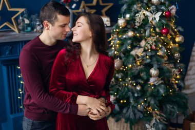 Adam kıza sarılıyor ve Noel ağacının yanında öpüşmek istiyor. 