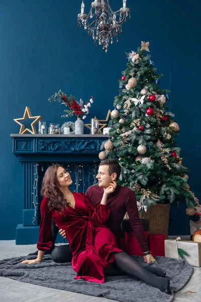 Casal apaixonado sentado perto da árvore de Natal e lareira. aconchegante r — Fotografia de Stock