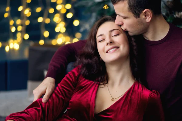 Pareja enamorada sentada cerca del árbol de Navidad. chico y chica cerrado — Foto de Stock