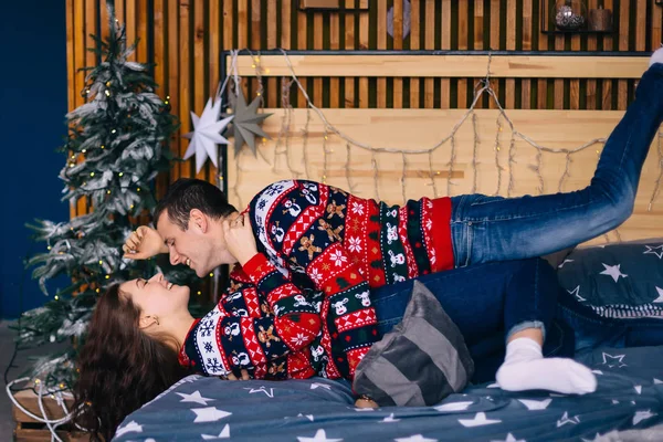 Cara e menina mentira na cama e sorriso no fundo árvore de Natal. — Fotografia de Stock