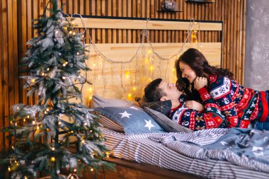 Lens fişeği. Erkek ve kız yatakta gıdıklanıyor. Noel ağacı ve garl