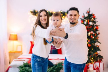 Ebeveynler ve küçük çocuklar Noel 'e yakın yatak odasında eğleniyorlar.
