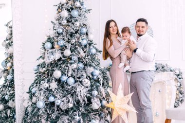 Mutlu aile güzel Noel ağacının yanındaki kameraya bakıyor.. 